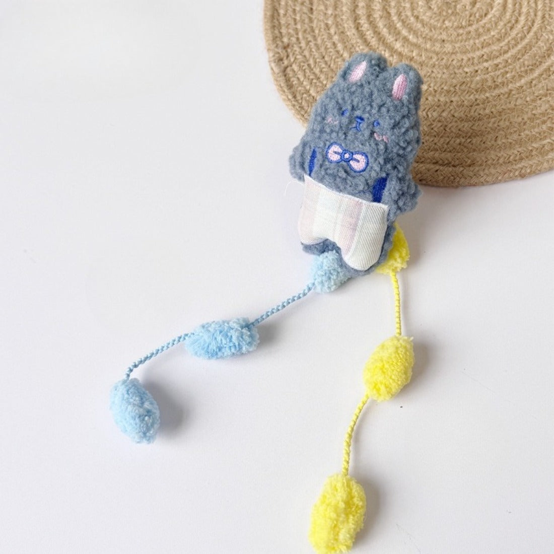 Moo cat toy with pom tail displayed on wooden surface with natural lighting