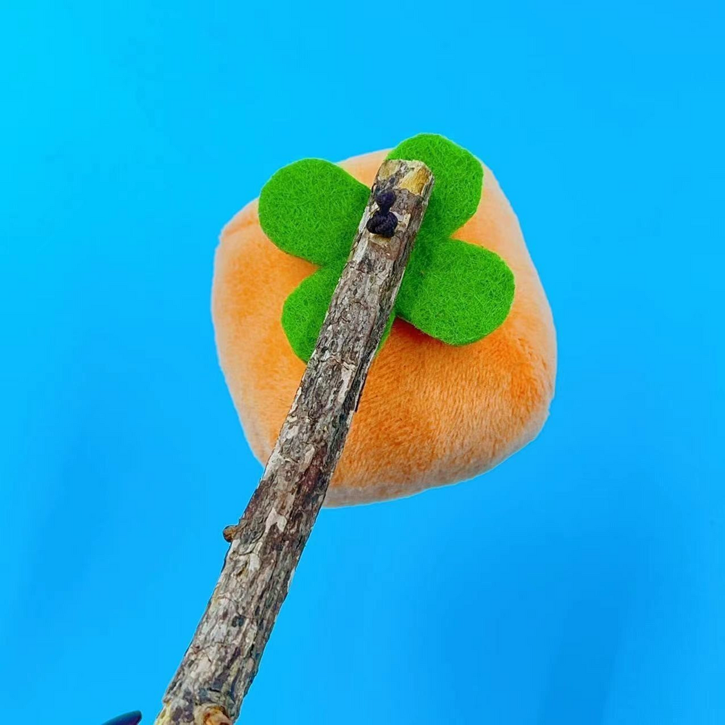 Persimmon cat toy, front detail showing the green four-lobed top and bark-textured stick