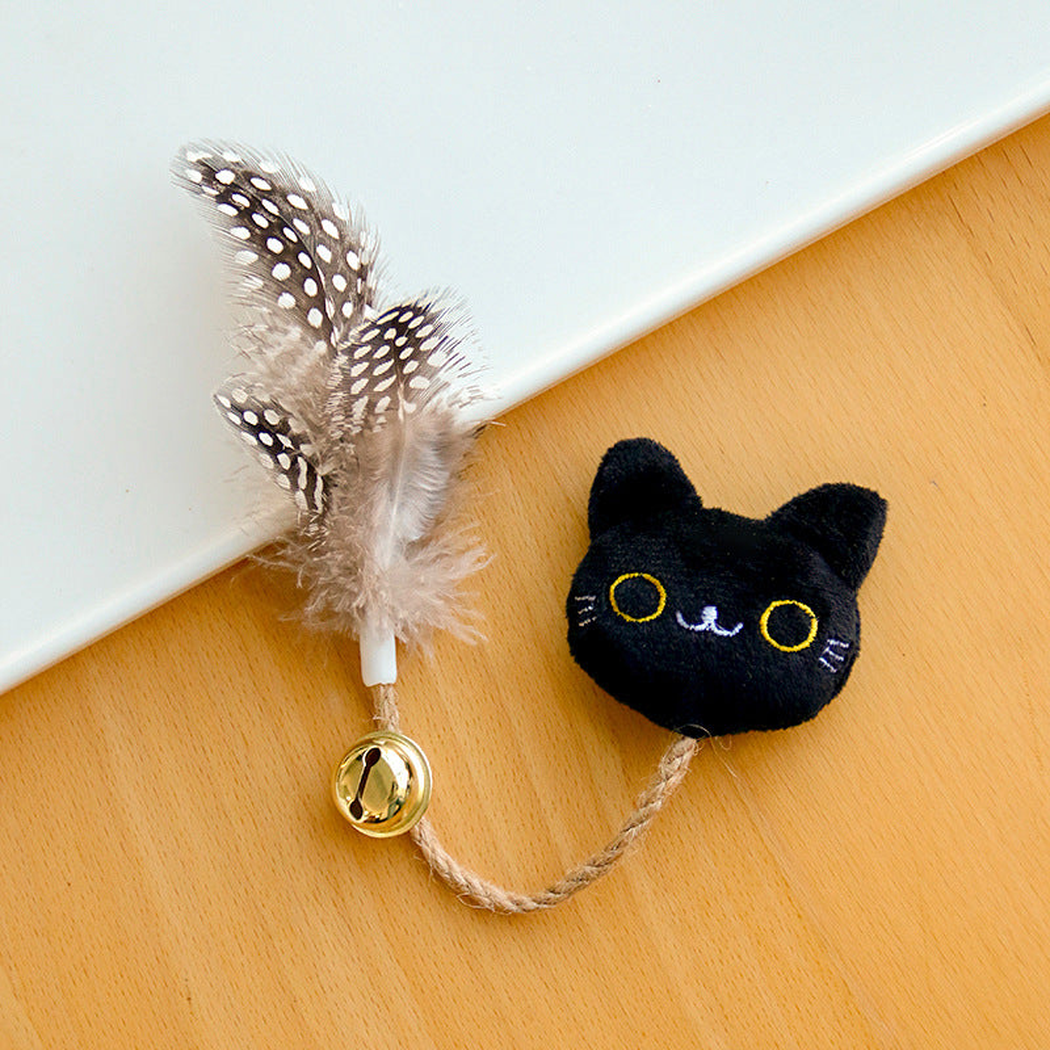 Black cat toy with embroidered yellow eyes, a braided cord, gold-colored bell and spotted feathers.