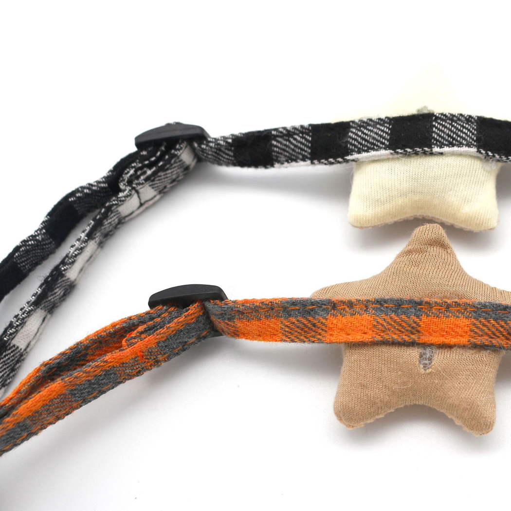 Close-up of plaid collar straps crossing the backs of two star ornaments