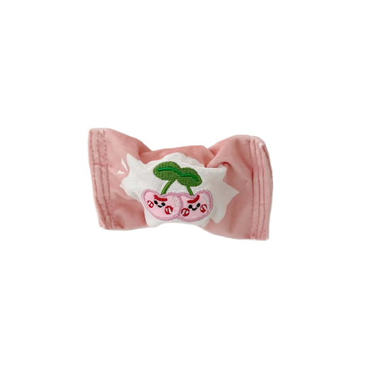 Pink candy-shaped dog toy with cherry face patch, front view