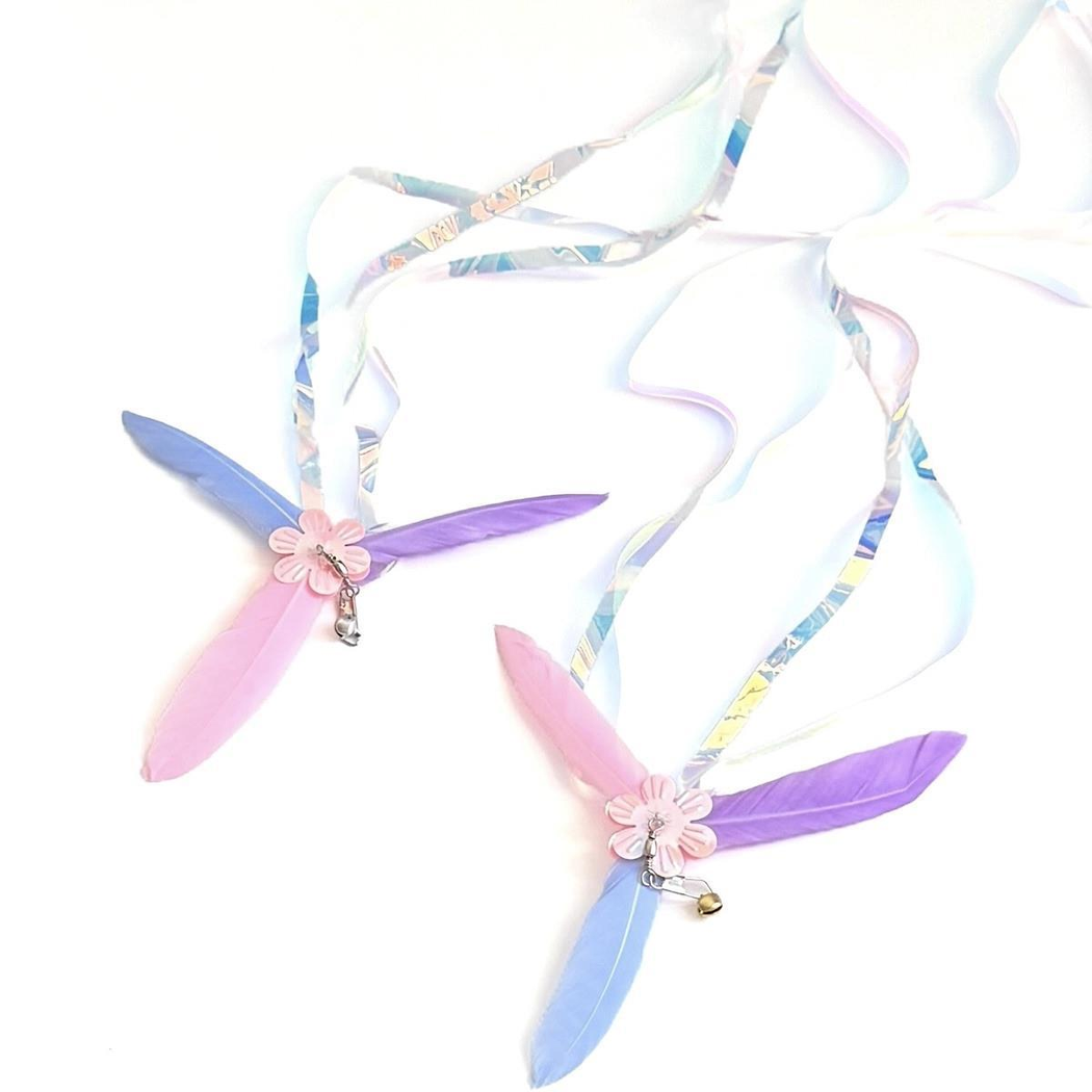 Two multicolor flower-centered cat teaser attachments with visible clasps, bells and curling streamers