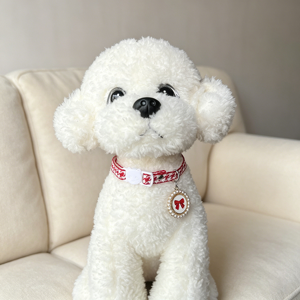Red houndstooth cat collar with bow charm worn by a white plush dog