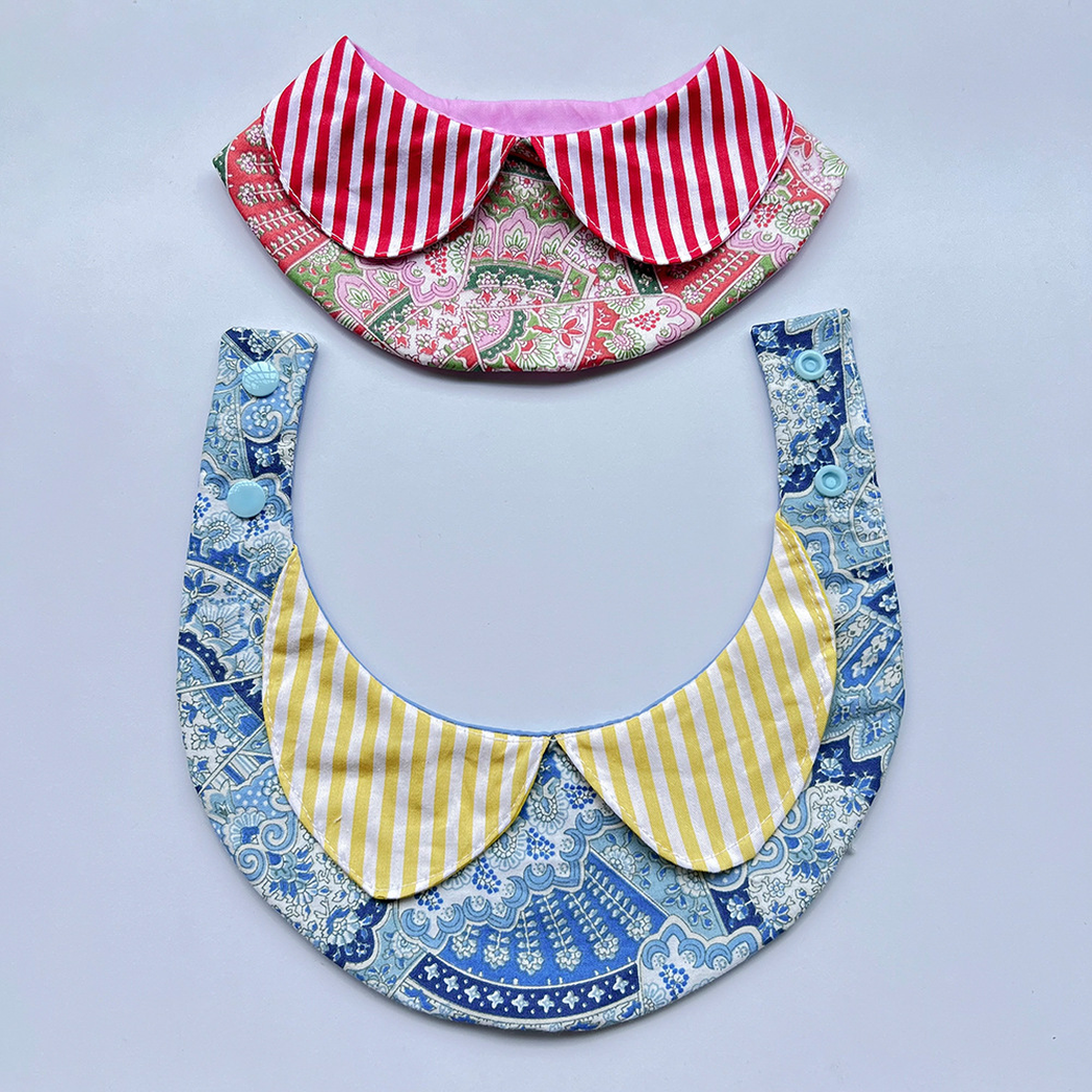 Yellow striped pet neckwear spread open to reveal snap fasteners, with a red design above.