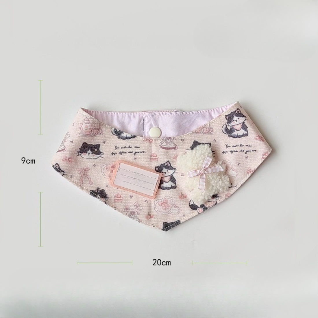 Baby wearing pink cartoon cat neck bib smiling and sitting in high chair