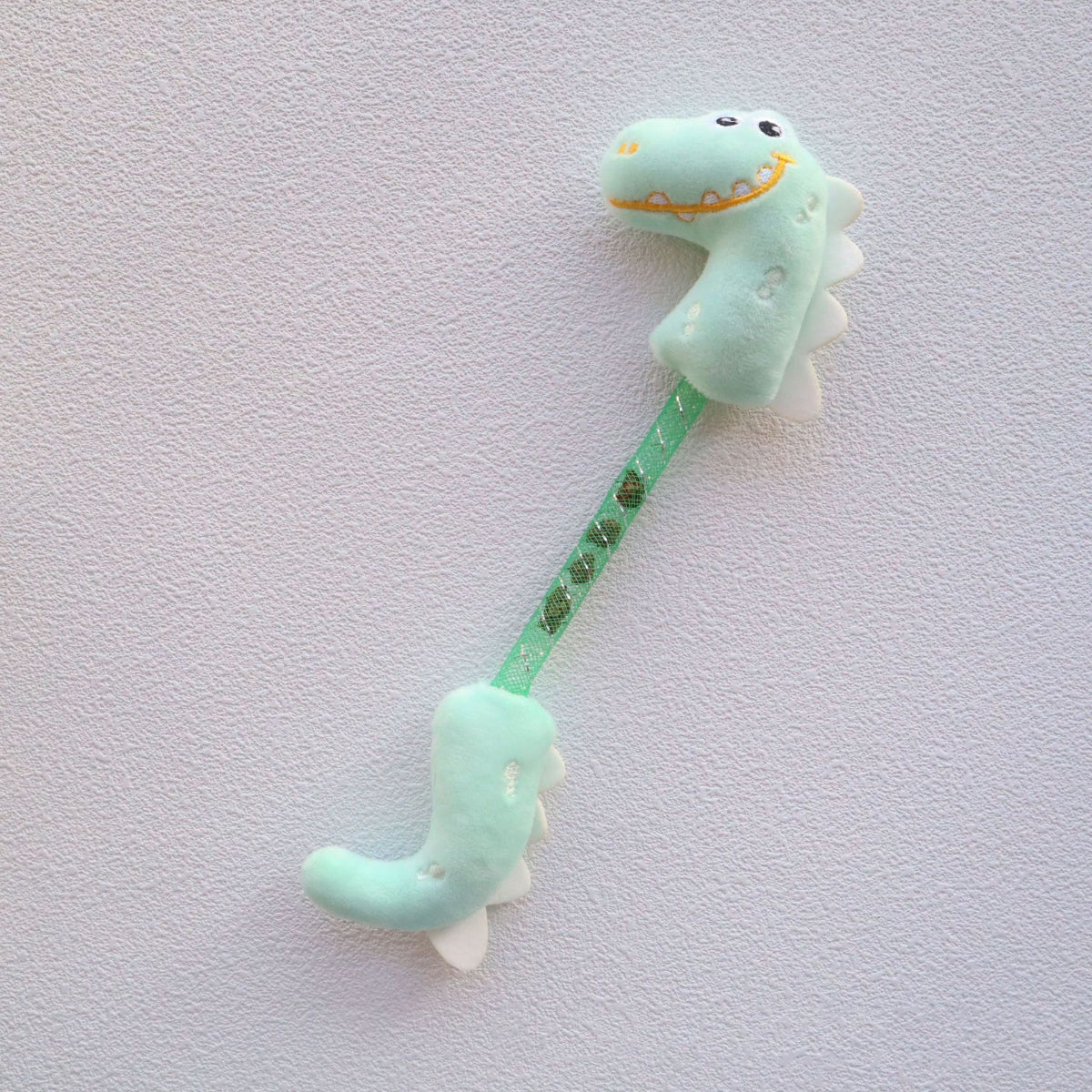 Moo Dinosaur cat toy with wiggly tail and glittery green surface on white background