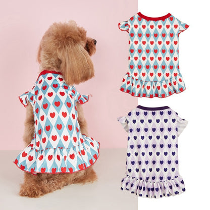 Small dog wearing Ozzie cute heart pattern dress standing on wooden floor
