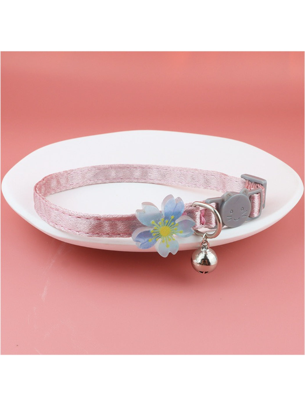 Mokka cat collar with pastel floral design and small silver bell on a wooden surface