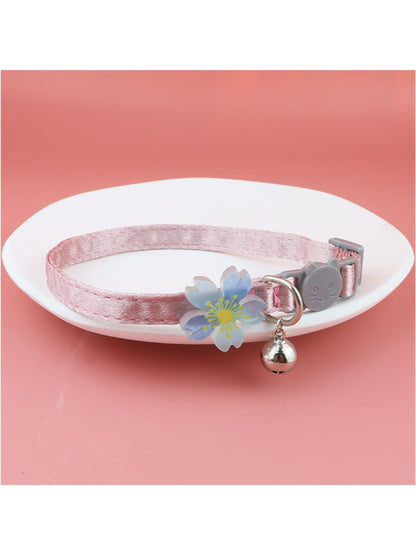 Mokka cat collar with pastel floral design and small silver bell on a wooden surface