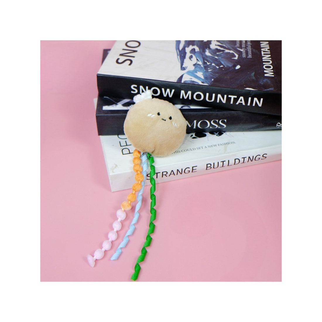 Moo fruit plush cat toy with ribbons held in hand to show size