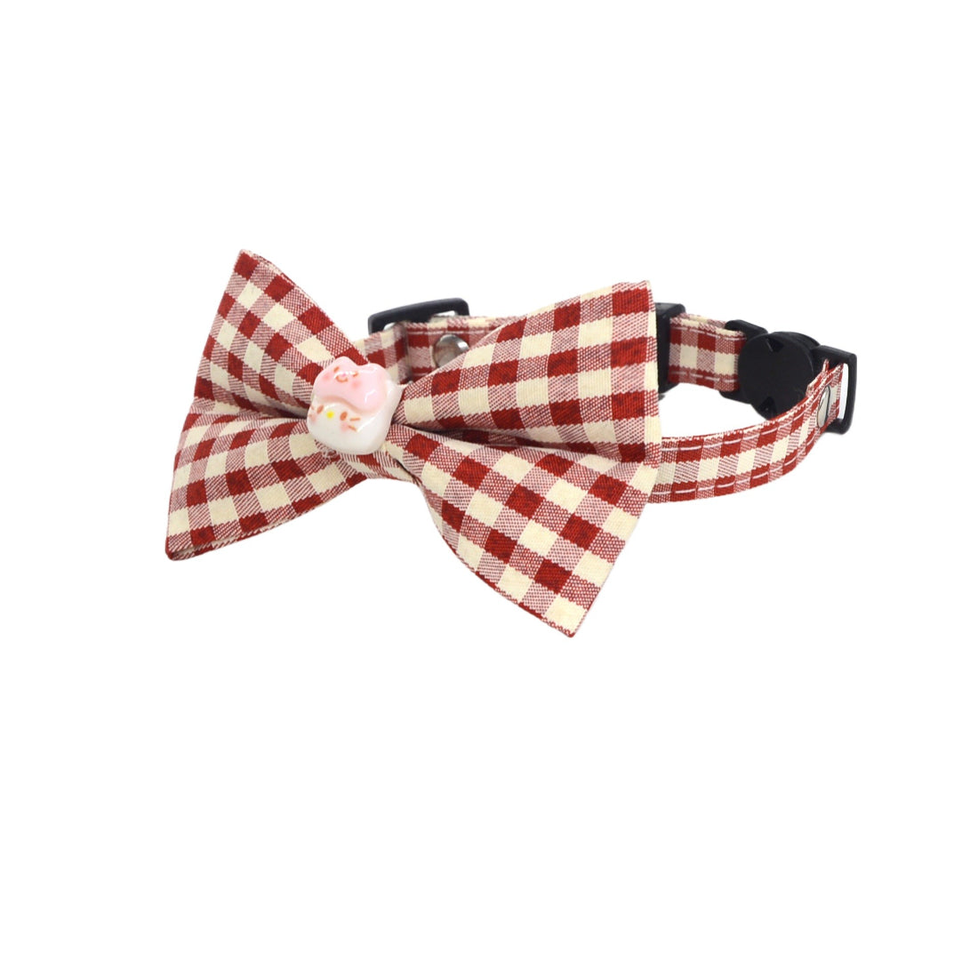 Close-up of Mokka cat collar bow detail with attached charm on brown fabric