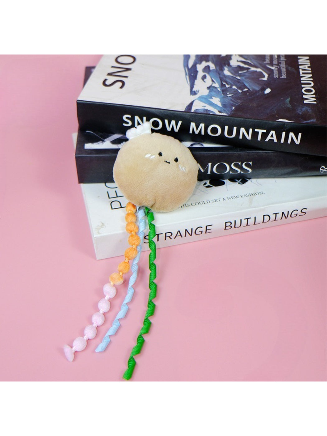 Moo fruit plush cat toy with ribbons photographed from above on a light background
