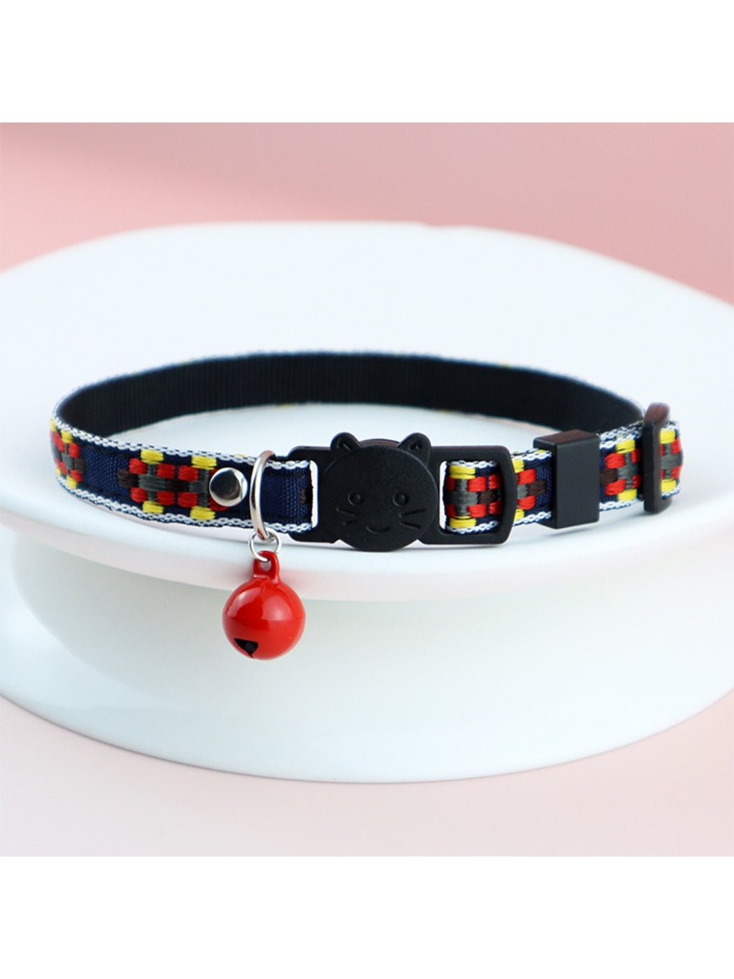 Mokka cat collar displayed next to a small bell accessory
