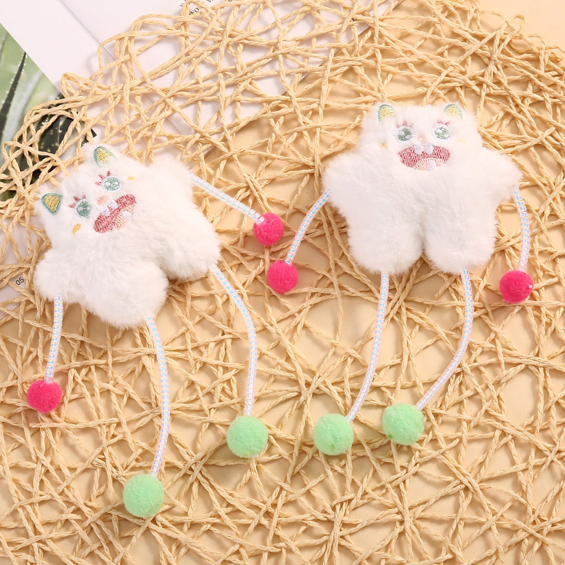 Close-up of Moo plush cat toy showing soft fabric and pom poms