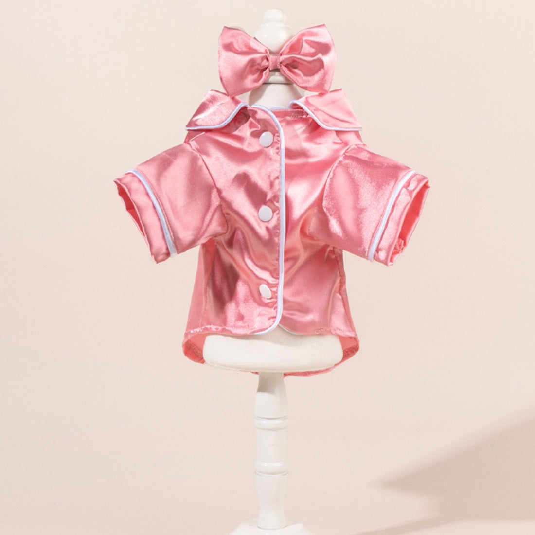 Small dog wearing a chic satin shirt with a bow, standing on a white background