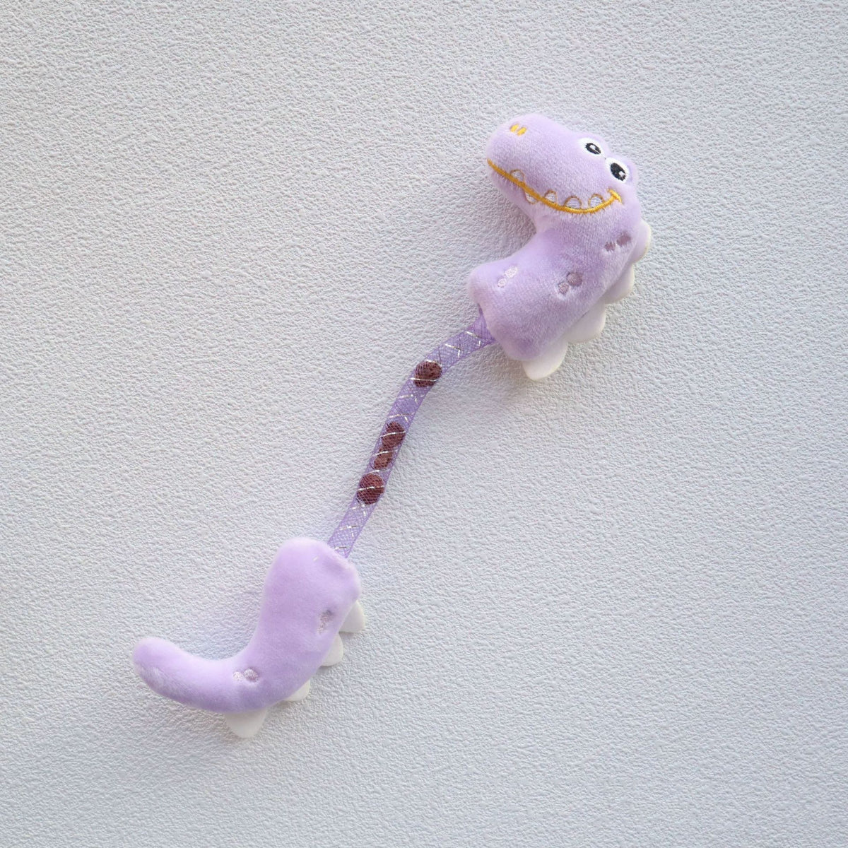Side view of Moo Dinosaur cat toy highlighting textured glitter fabric and embroidered eyes