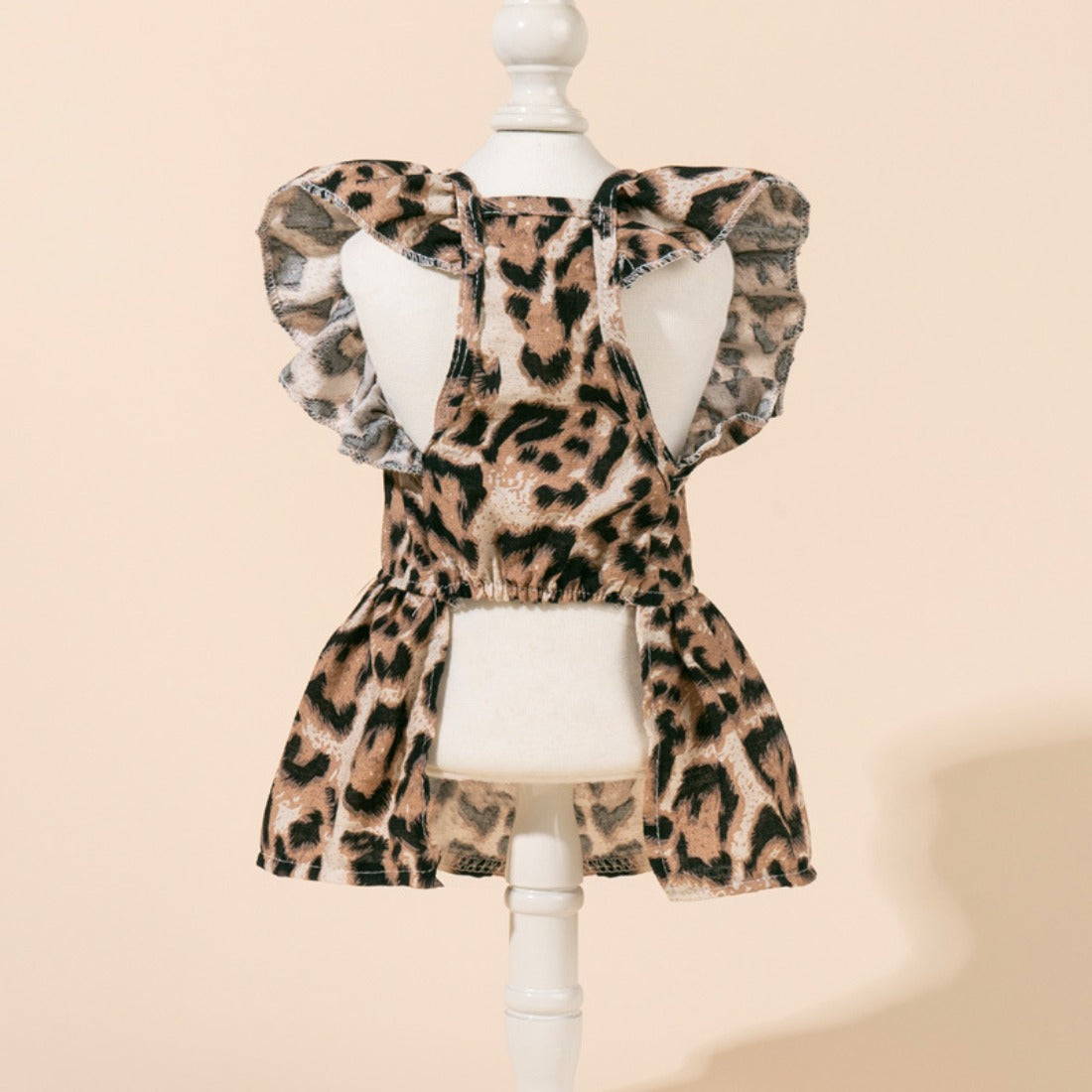 Leopard dog dress laid flat, highlighting the bow and fabric texture