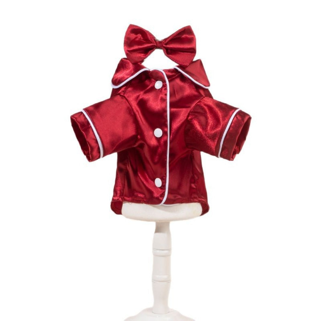 Small dog sitting while wearing a smooth satin shirt with a decorative bow