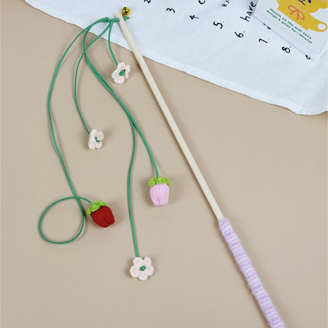 Cat playing with Moo Fruit Wand toy featuring bright orange pom pom
