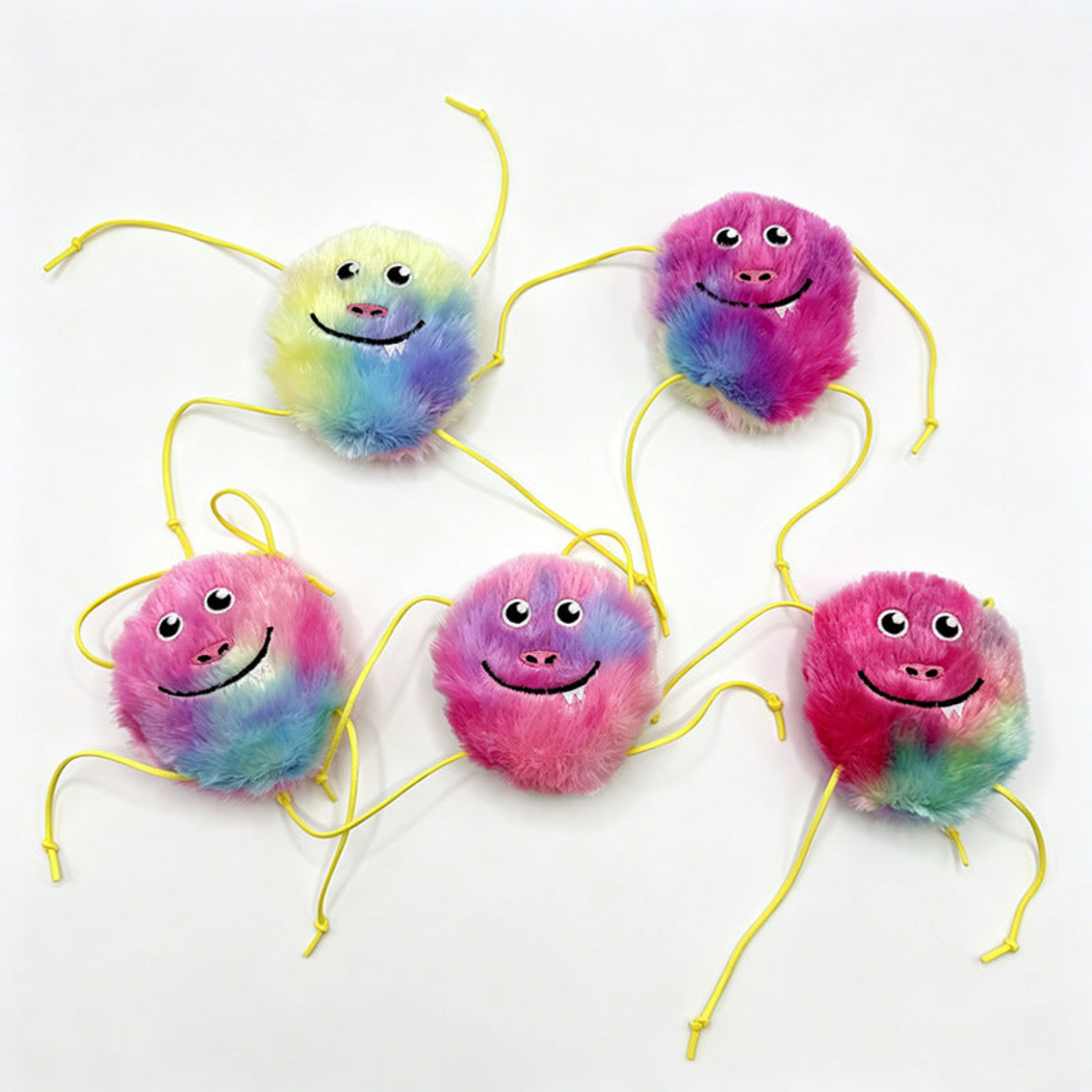 Monster cat toys with furry smiling faces and yellow cords displayed together