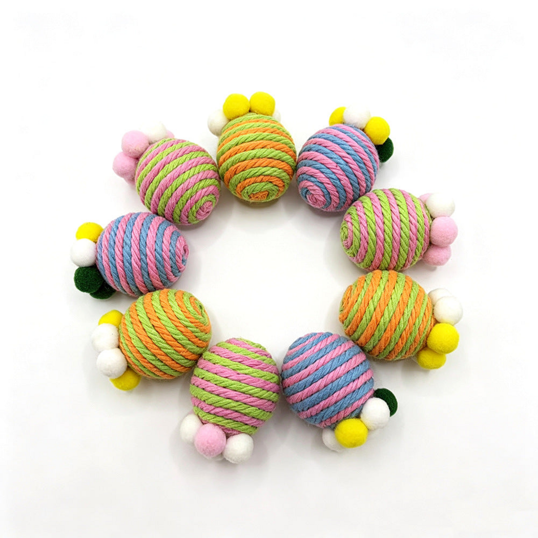Striped cat toys with pom-poms arranged in a circle on white
