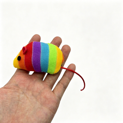 Rainbow-striped mouse-shaped cat toy resting on an open hand, with its red cord tail visible