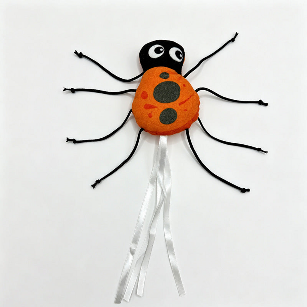 Ladybug cat toy with an orange spotted body, black head, eight cord legs and white ribbon streamers