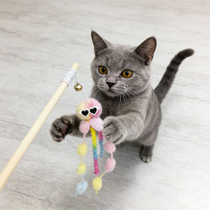 Gray cat reaching for a pink octopus cat teaser toy with a visible bell