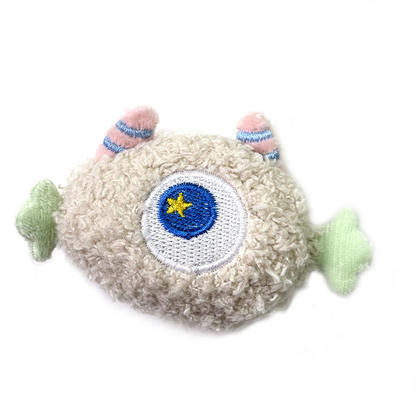 Beige cat toy with a central embroidered eye and green side appendages