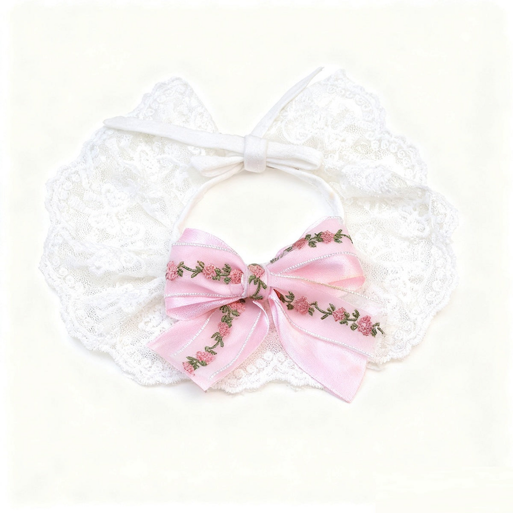 Pink Pet Neckwear spread flat with a floral bow, white tie straps and scalloped lace-look edge