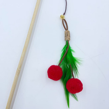 Close-up of the cat toy's red fuzzy balls, green feathers and connection to the wand cord