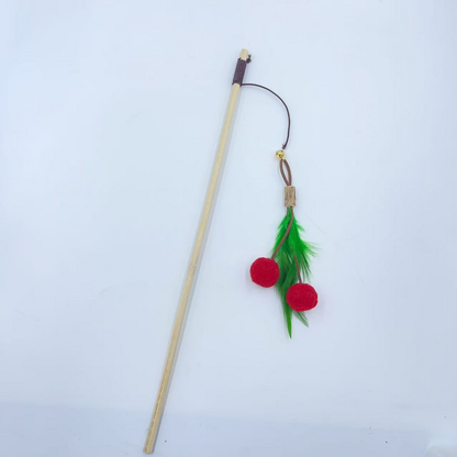 Wand cat toy with a long pale stick and dangling red balls and green feathers