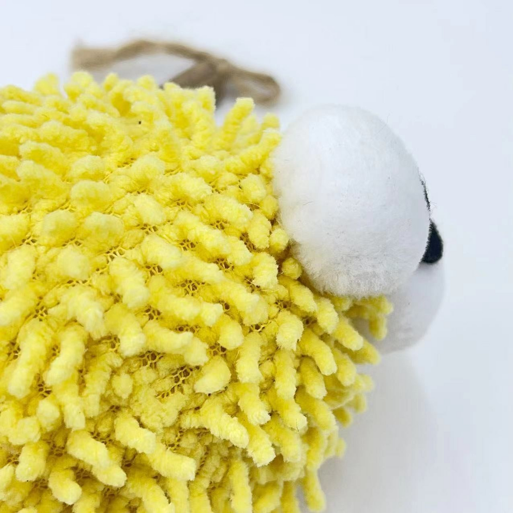 Close-up of the yellow ball cat toy's dangling tufts and protruding eyes