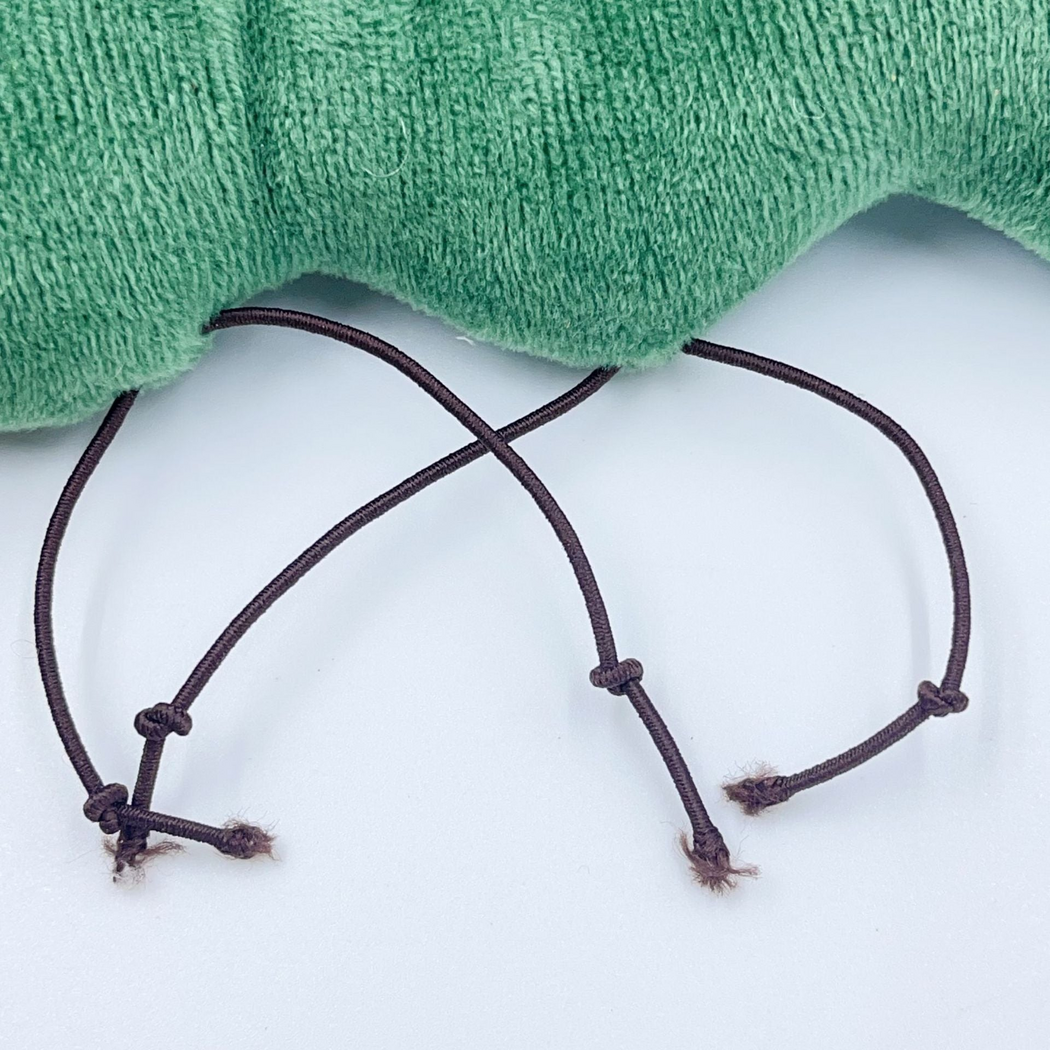 Close-up of dark knotted cord legs with frayed ends beneath the green cat toy