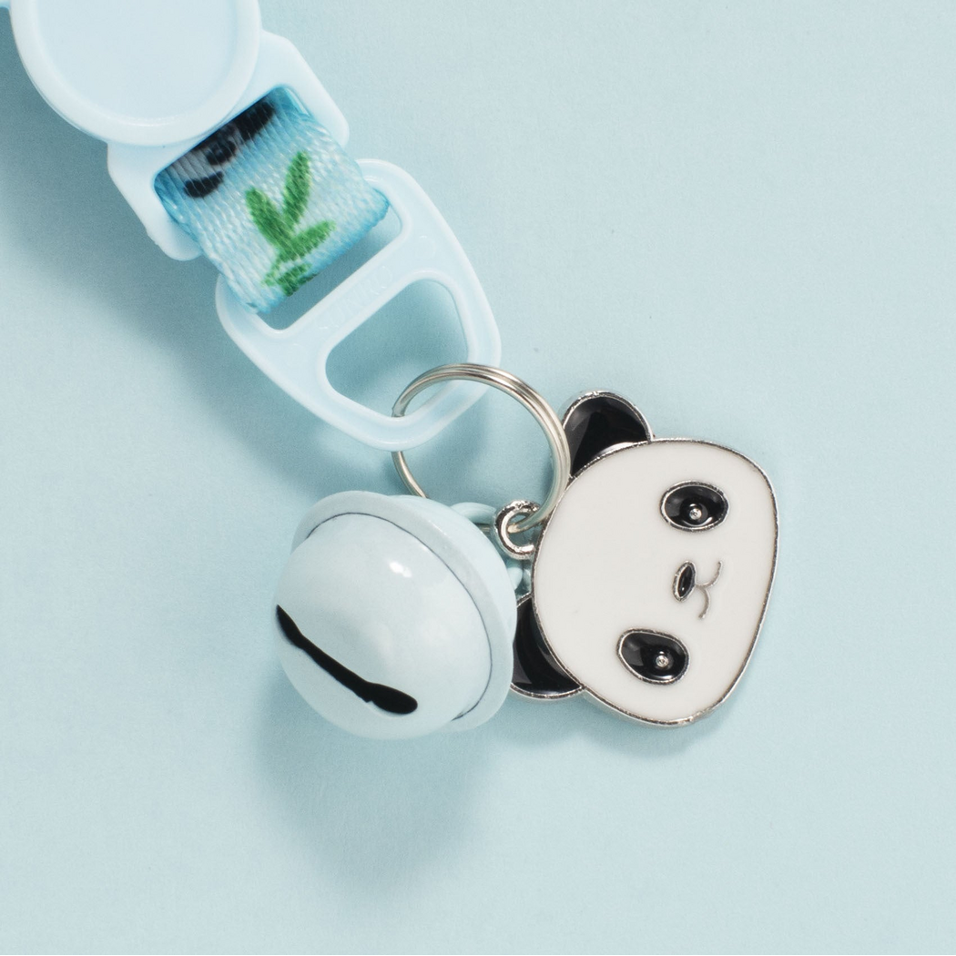 Close-up of a Cat Collar bell, panda-face charm and metal attachment ring