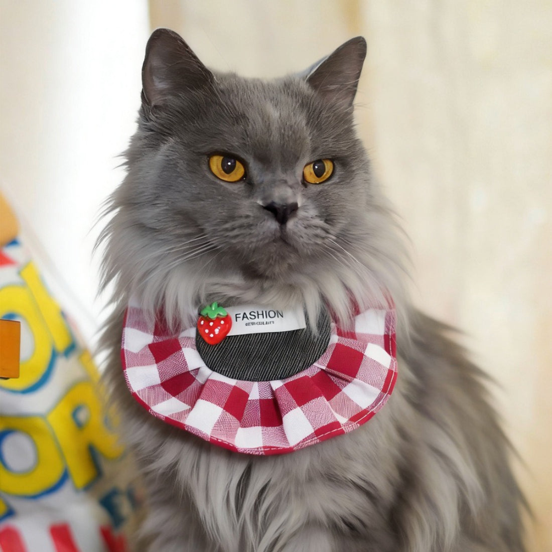 Strawberry gingham cat bib displayed flat with adjustable neck strap visible