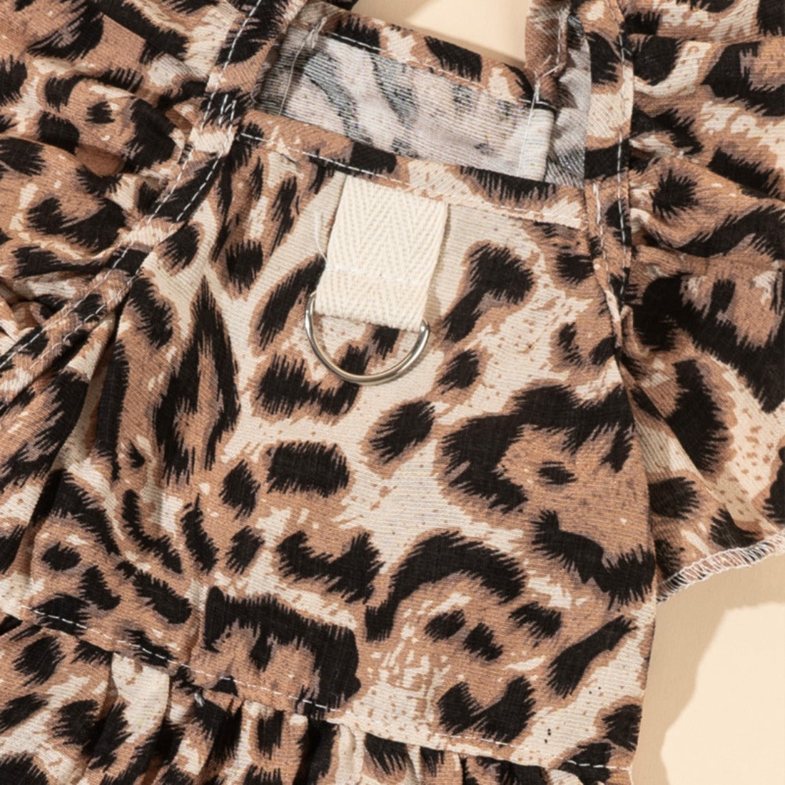 Dog wearing the leopard print dress with bow, sitting and facing forward