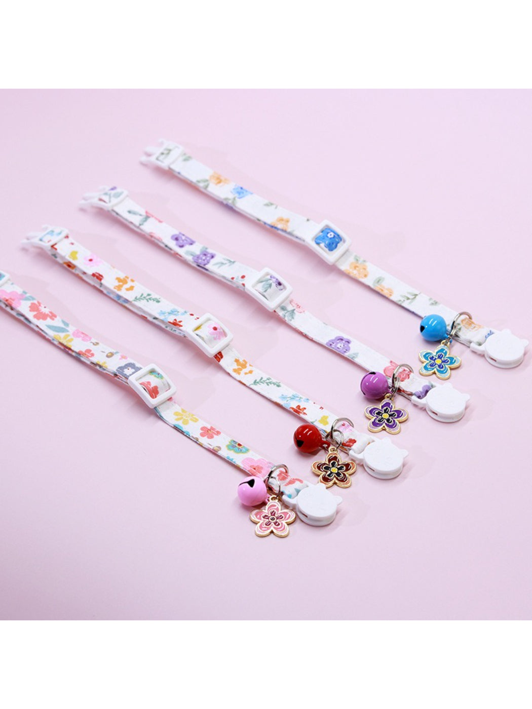 Close-up of Mokka Floral Charm Bell Cat Collar with pink and white flowers on fabric