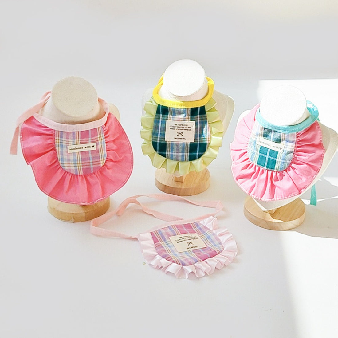 Mokka plaid ruffle cat bib displayed flat showing red and white check pattern