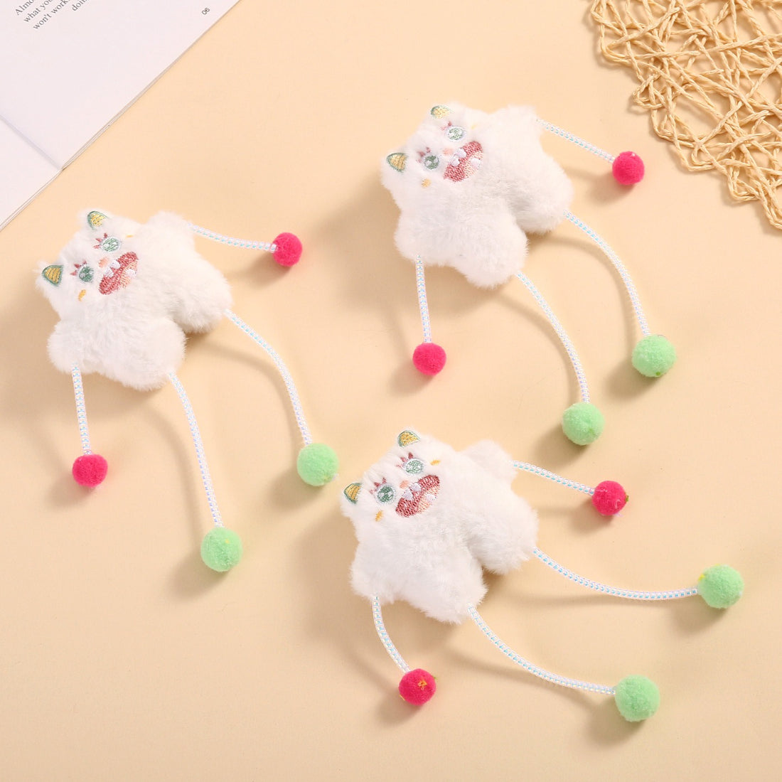 Moo plush cat toy with pom poms displayed on a white background