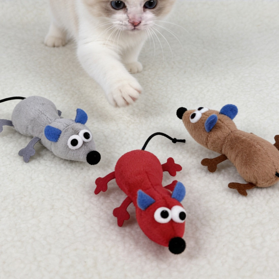 Moo mouse cat toy lying on a wooden surface with visible tail and whiskers