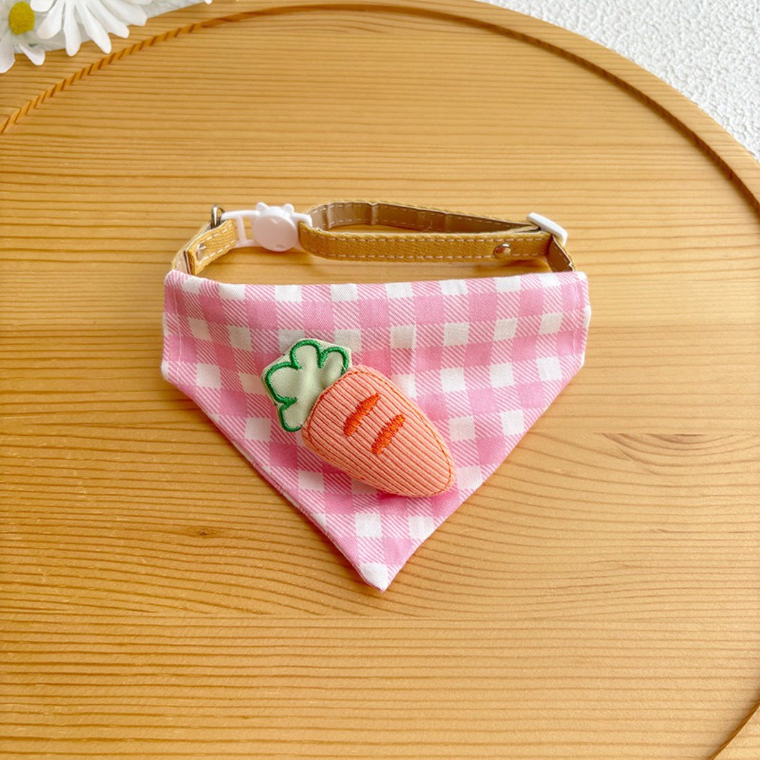 Cat wearing pink gingham bandana sitting on wooden floor