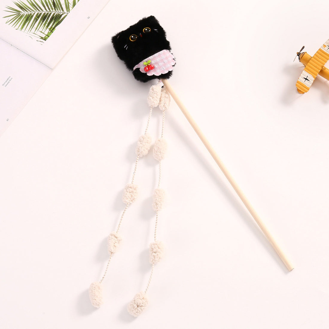 Cat playing with Moo plush cat teaser wand toy featuring vibrant feathers and plush elements