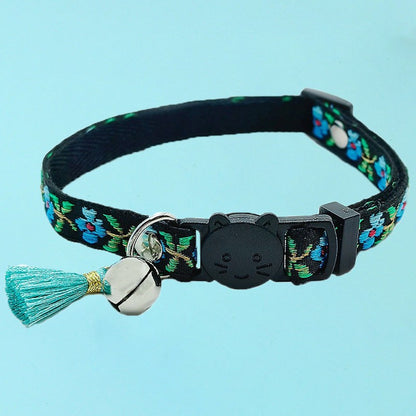 Mokka floral cat collar with tassel and bell shown coiled on surface