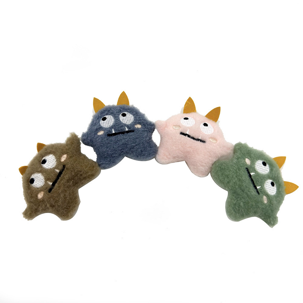 Brown, blue, pink and green two-eyed monster cat toys arranged in an arc