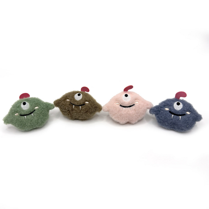 Green, brown, pink and blue one-eyed monster cat toys standing in a row