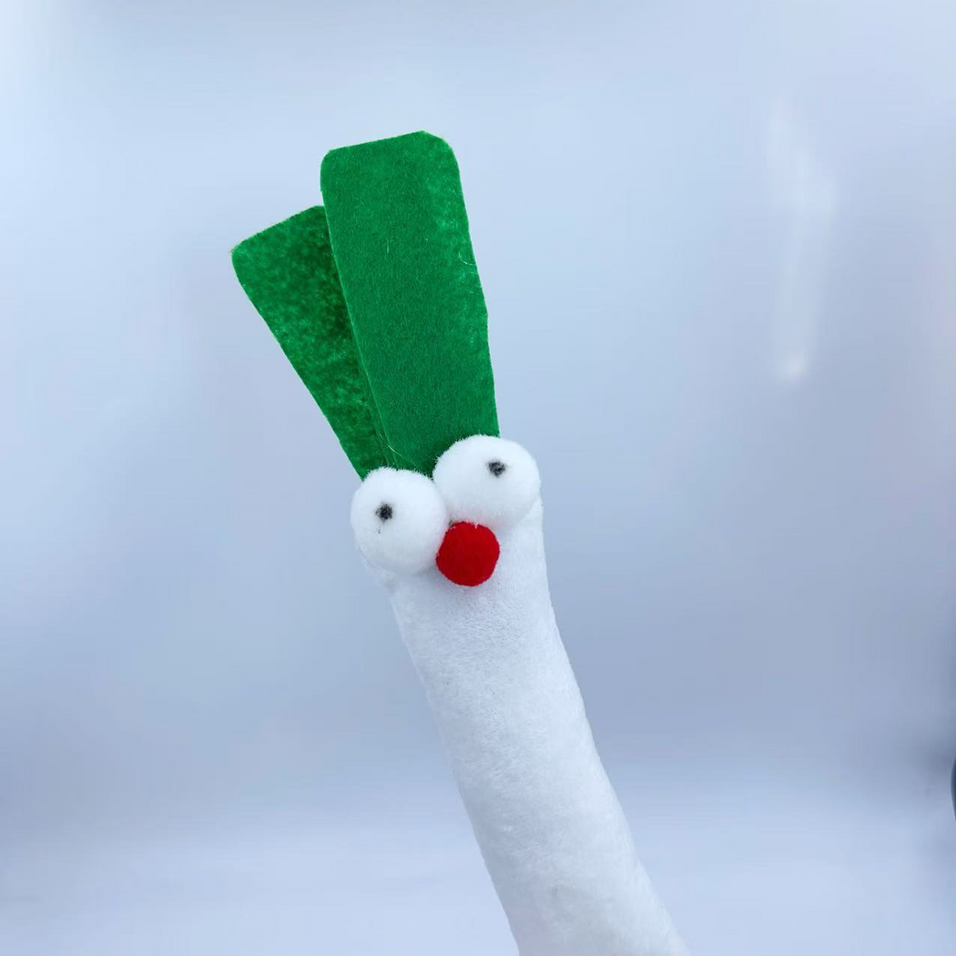 Angled upper-body detail of the scallion-shaped cat toy showing its face and layered green leaves