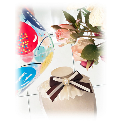 Ivory Pet Neckwear viewed at an angle, showing the layered brown bow and pearl-look centerpiece