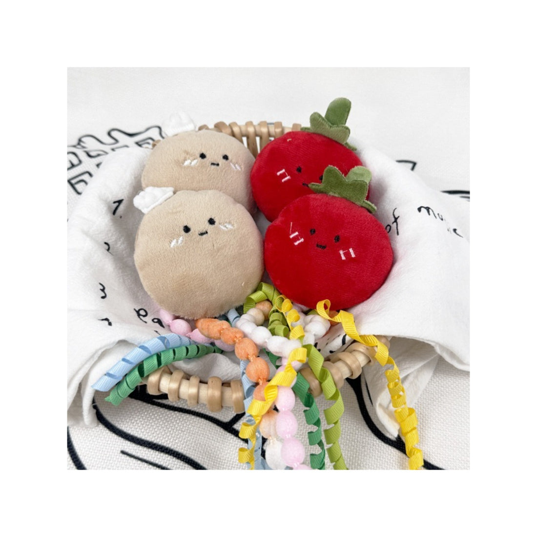 Moo fruit plush cat toy with colorful ribbons on a white background