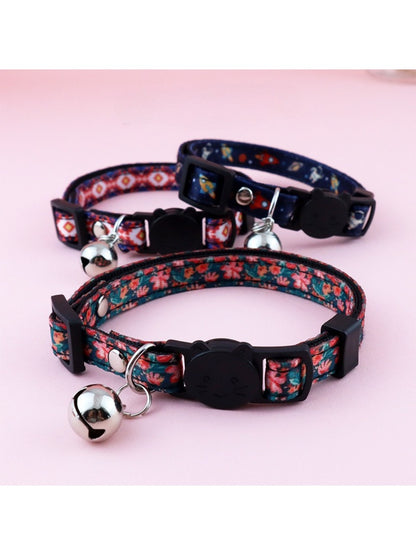 Close-up of Mokka floral print bell cat collar with pink and green flowers on beige background